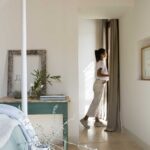 Rincón del dormitorio con mesa verde, marco antiguo, suelo de piedra clara y luz natural