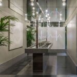 WC with a continuous grey stone basin, light bulbs, mirrors and a heartbeat line of light on the wall