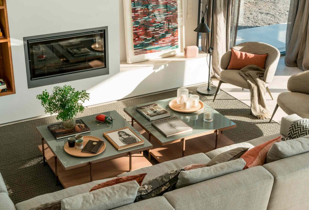Living room seen from above with a built-in fireplace, glass coffee tables and a grey sofa