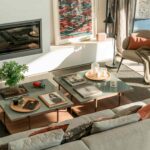 Living room seen from above with a built-in fireplace, glass coffee tables and a grey sofa