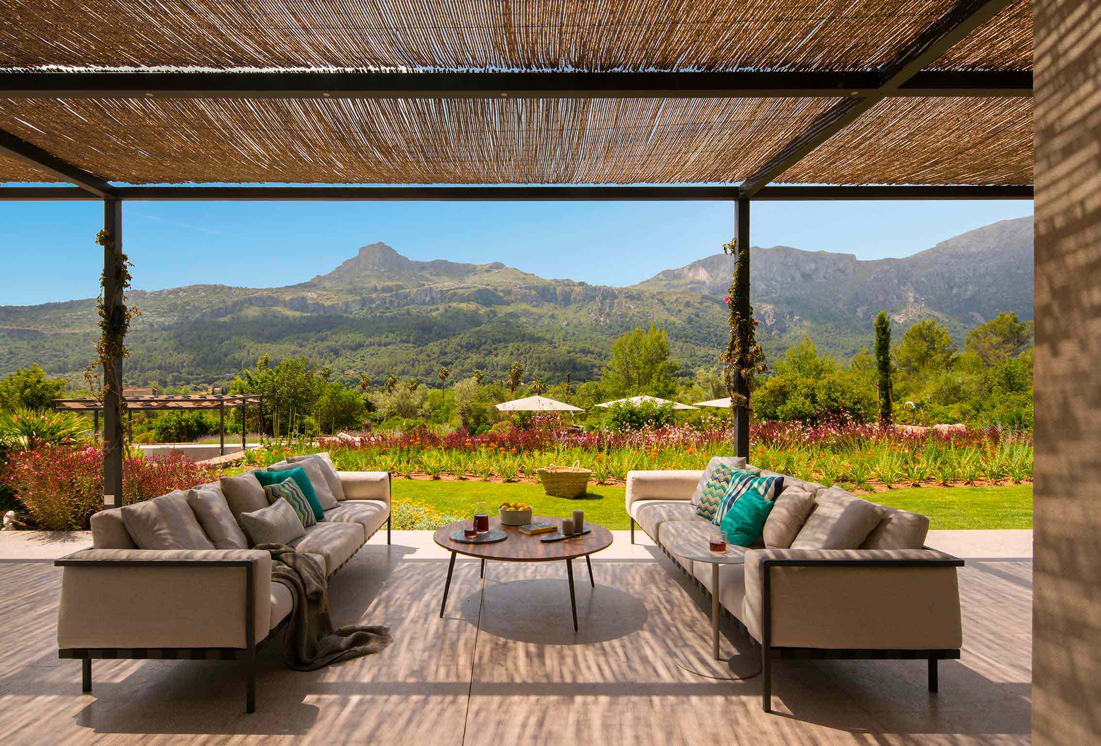 Überdachte Terrasse mit Pergola aus Schilfrohr, Sofas und Couchtisch vor der Serra de Tramuntana