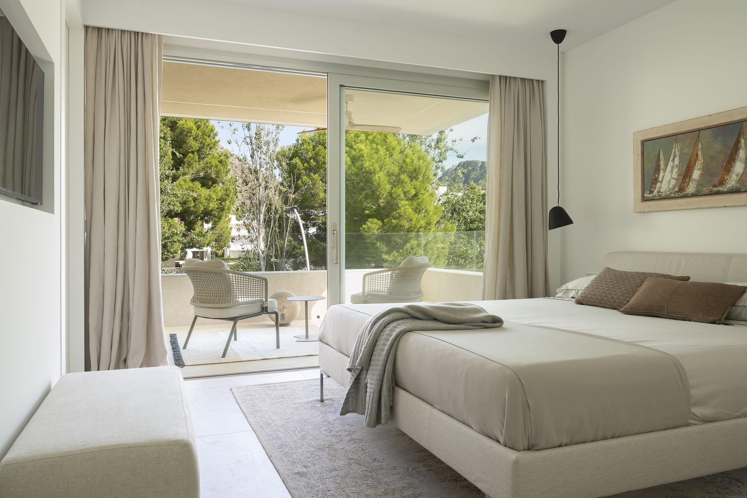 Helles Schlafzimmer in Sandtönen mit Leinenvorhängen und Balkon mit Blick auf die Pinien
