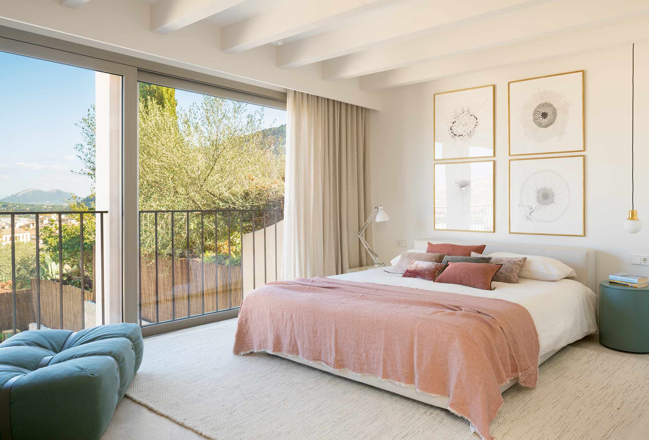 Schlafzimmer mit großem Bett, rosa Tagesdecke, weißen Balken und großem Fenster mit Balkon und Bergblick
