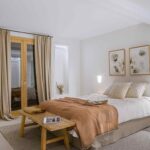 Schlafzimmer mit terrakottafarbener Decke, Holzbank, beigen Vorhängen, zwei Bildern und beleuchteten Nischen