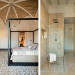 Dormitorio con cama de estructura negra bajo bóveda de piedra y baño con ducha de mármol beige