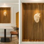 Timber-slat niche with white heart sculpture, above a table with chairs