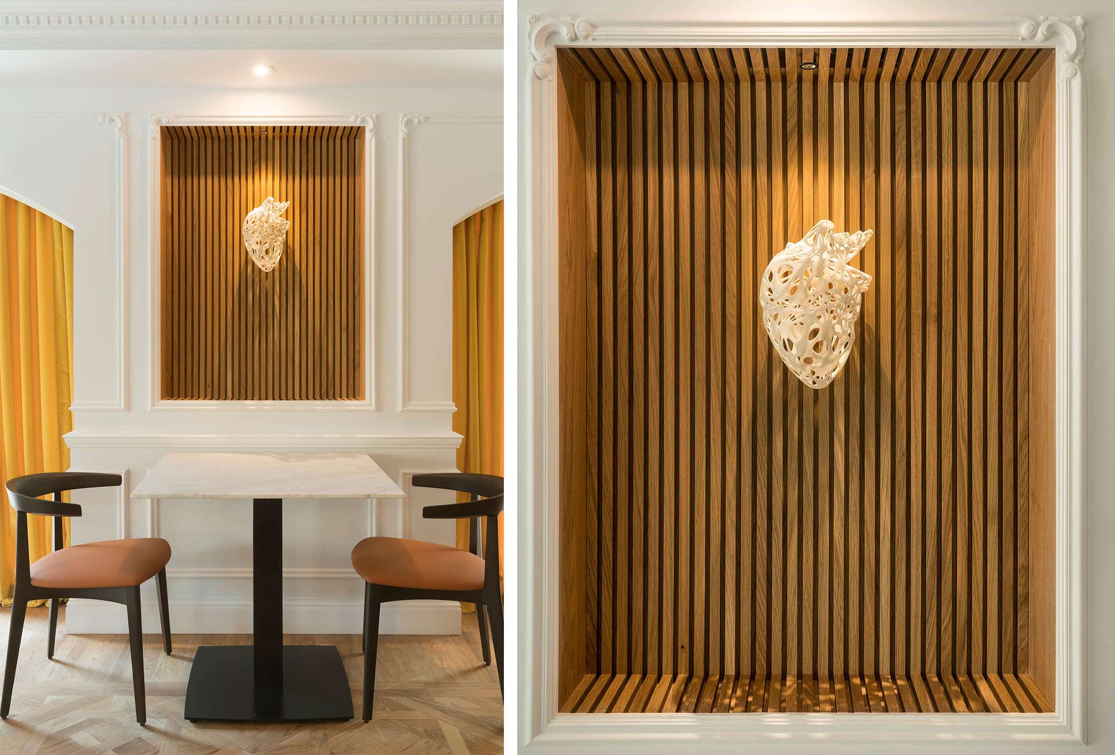 Timber-slat niche with white heart sculpture, above a table with chairs