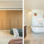 Heller Holzschrank im Schlafzimmer und weiße ovale Badewanne mit Glasdusche im Hintergrund