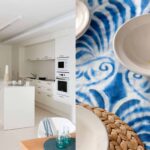 Weiße Küche mit Kochinsel und Einbaugeräten, dazu Detail einer blauen Tischdecke mit Keramikschalen