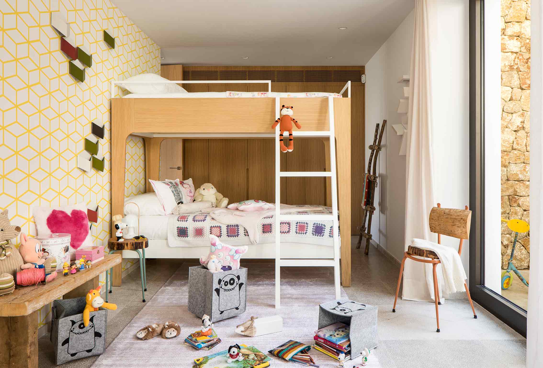 Dormitorio infantil con litera de madera y blanco, papel pintado amarillo geométrico y juguetes