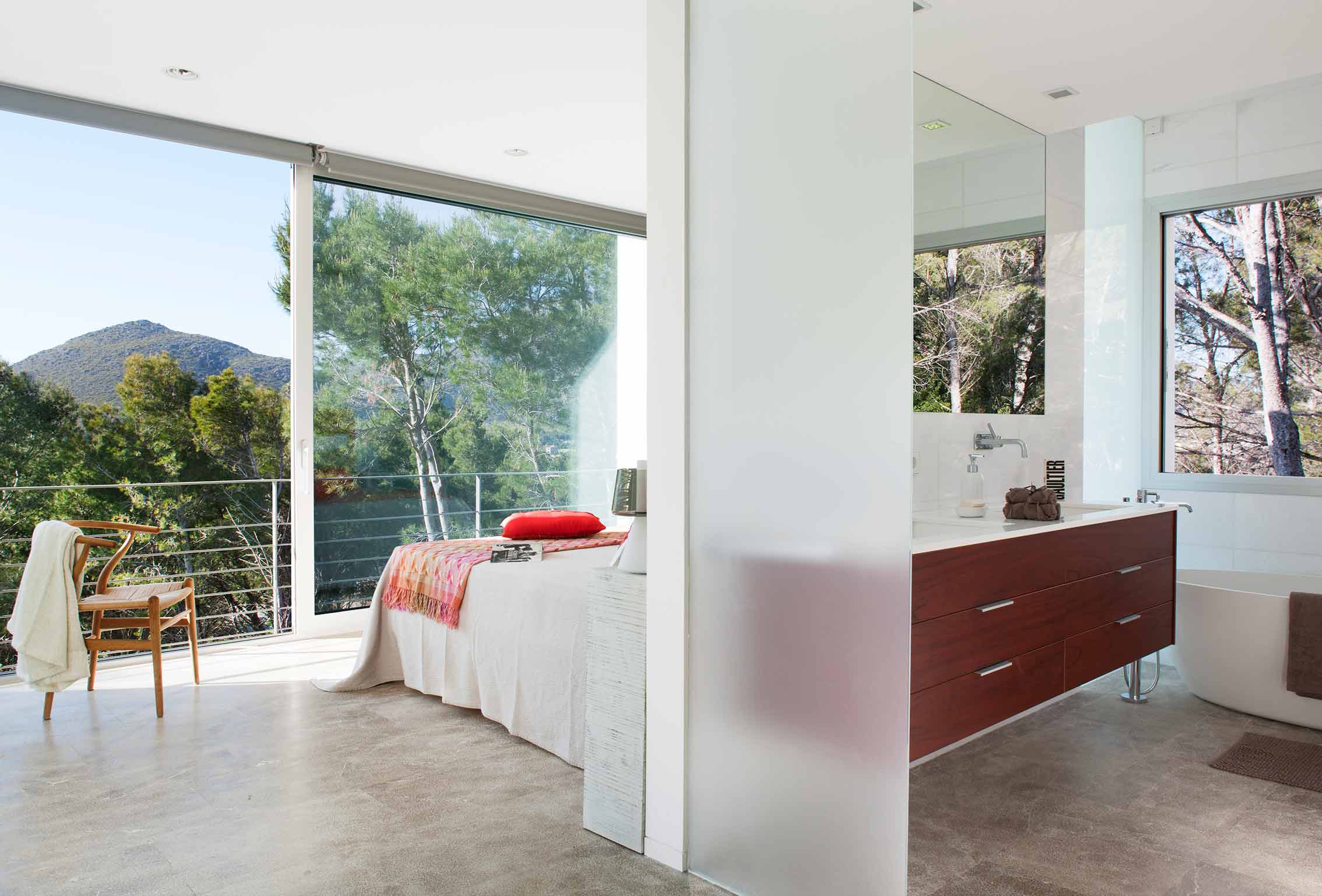 Dormitorio abierto al baño con mueble de madera oscura, bañera exenta y vistas a la montaña
