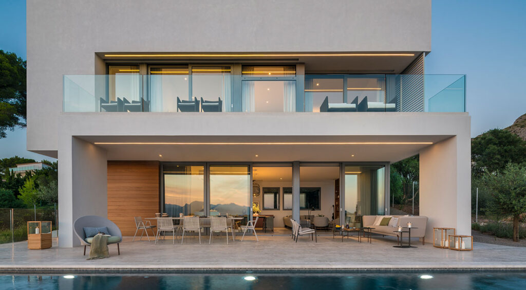 Alfabaguera façade at dusk with a lit terrace, swimming pool and glass balcony
