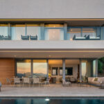 Alfabaguera façade at dusk with a lit terrace, swimming pool and glass balcony