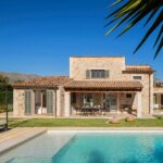 Casa Bon Estatge, a stone house with a porch, garden and swimming pool, and a mountain in the background