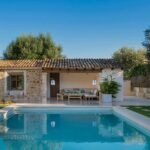 Small stone house with a porch and seating area beside the swimming pool surrounded by olive trees