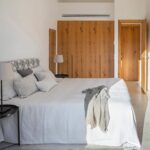 Bedroom with white bed linen, light wood wardrobes, a natural fibre rug and warm light