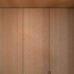 Detalle de armarios empotrados de madera clara con tirador integrado y foco en el techo