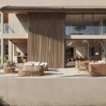 Façade with vertical timber lattice, terrace with wicker furniture and glass balconies