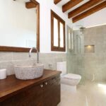 Baño con espejo de marco de madera, grifo curvo, inodoro blanco y ventana con luz natural