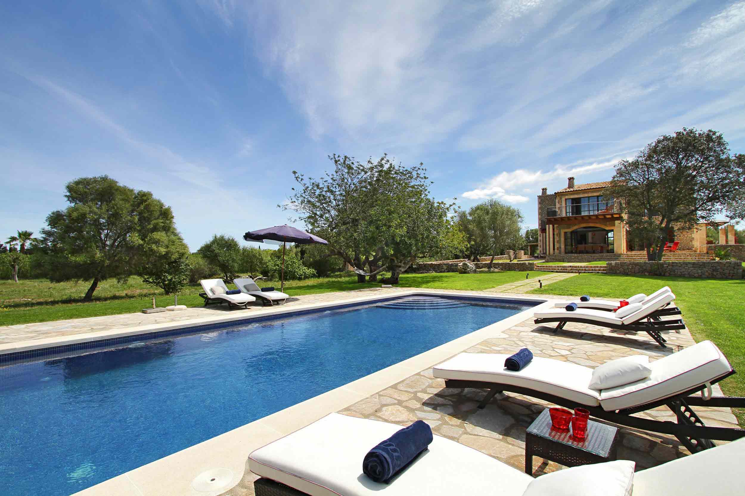 Villa Marina, piscina azul con tumbonas blancas y jardín, con la casa rústica de piedra al fondo