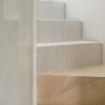 Treppendetail mit Setzstufen aus weißem Lochblech und beigen Steinstufen
