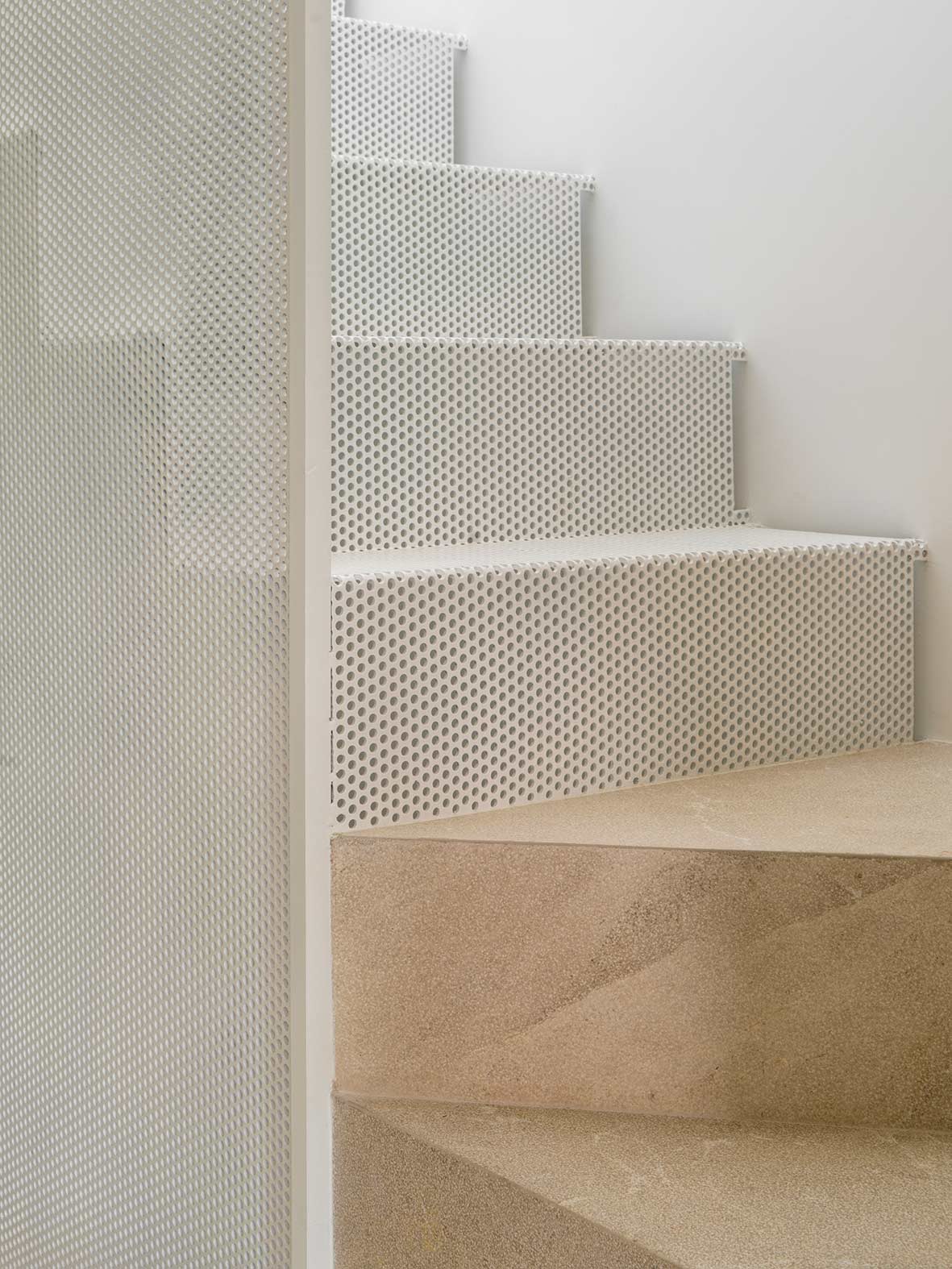 Treppendetail mit Setzstufen aus weißem Lochblech und beigen Steinstufen
