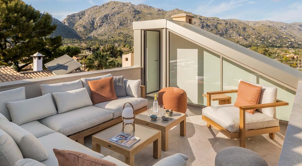 Dachterrasse von SJ13 mit Outdoor-Sofa, Holztischen und Bergblick
