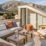 Dachterrasse von SJ13 mit Outdoor-Sofa, Holztischen und Bergblick