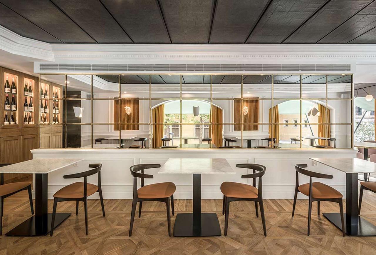 Speisesaal mit Marmortischen, Holzstühlen, Spiegeln mit goldenen Rahmen und Parkett