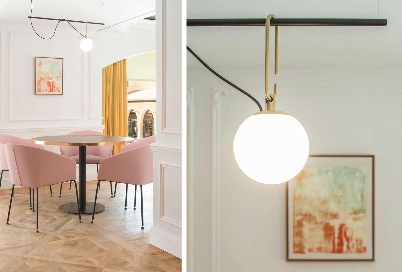 Runder Tisch mit rosa Stühlen und Detail einer Kugelleuchte mit goldenen Akzenten