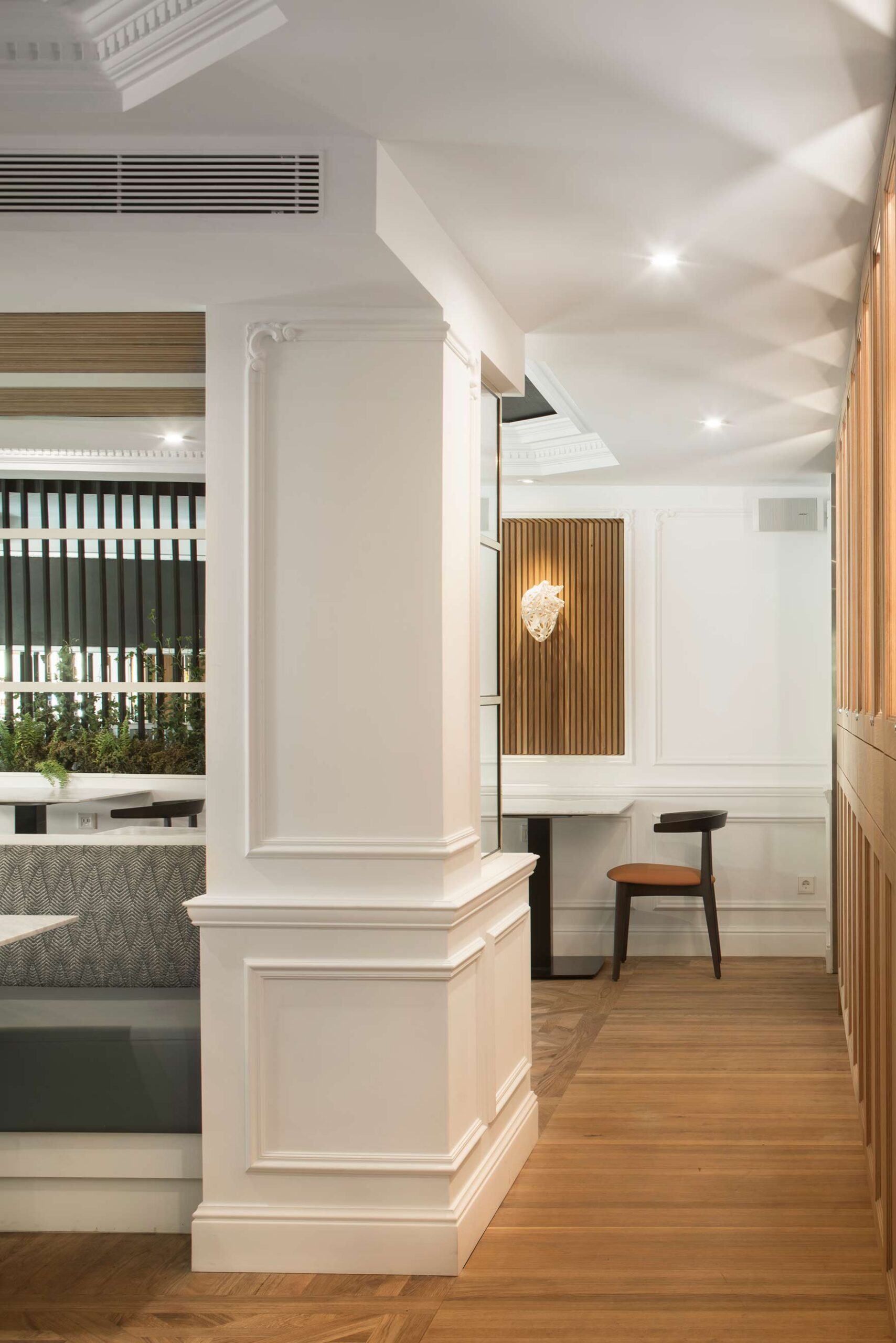 White pillar with mouldings, wooden parquet and a slatted niche with a heart sculpture at the back