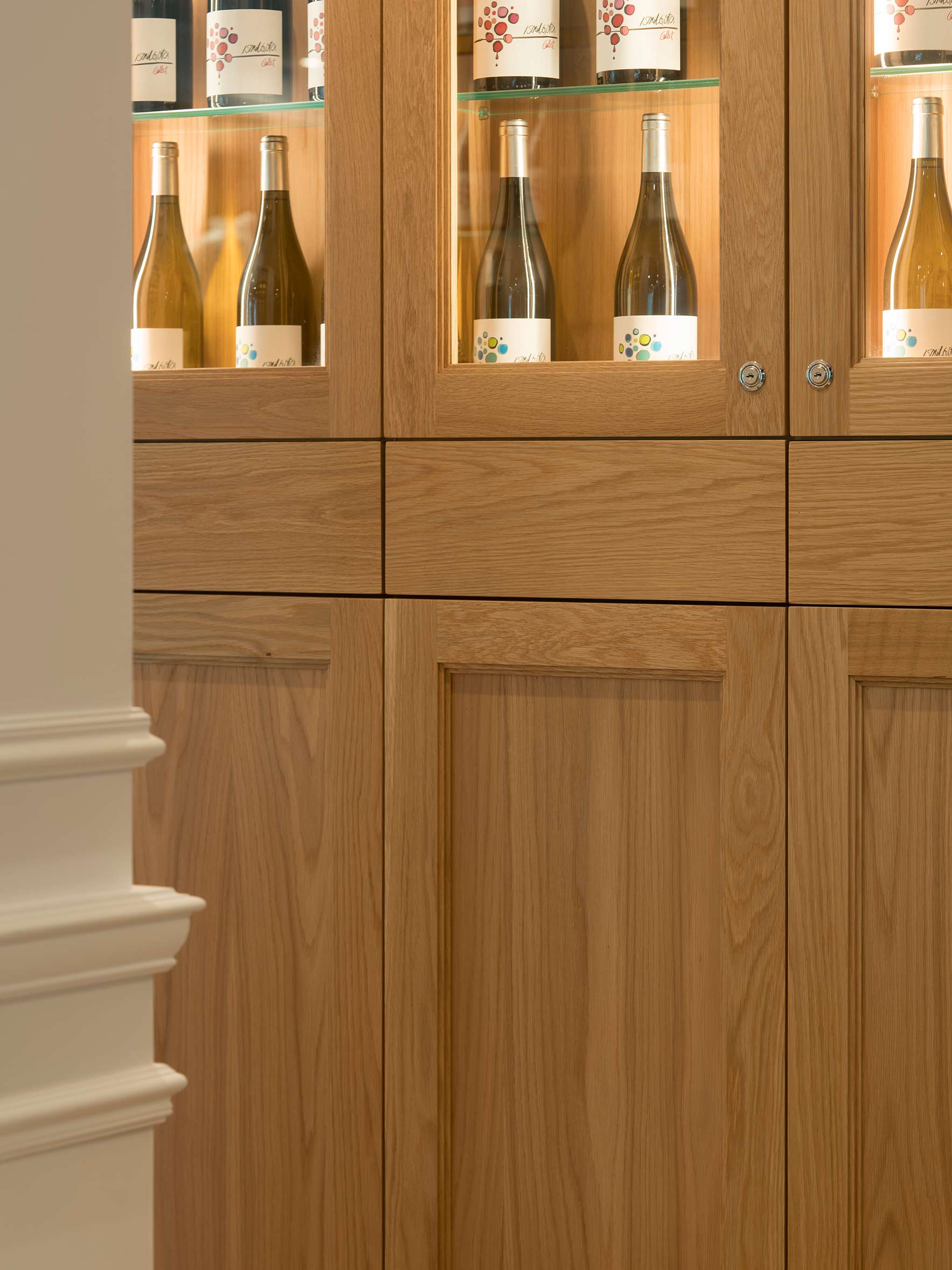 Detail of a light timber cabinet with glass display cases and wine bottles