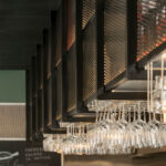 Detail of black metal mesh shelving above the bar with wine glasses hanging