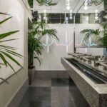 Heartbeat line of light reflected in the washroom mirrors, with palm trees, light bulbs and a stone basin