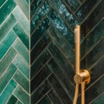 Detalle de pared de ducha con azulejos verdes esmaltados en espiga y ducha de mano dorada