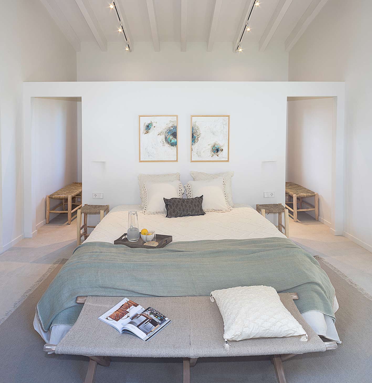 Symmetrisches Schlafzimmer mit Doppelbett, graugrünem Plaid, Bank am Fußende und weißer Balkendecke