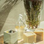 Holztablett mit Seifen, Spender und Vase mit rötlichen Zweigen im Sonnenlicht