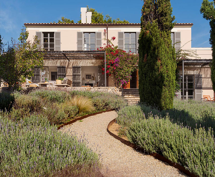 Gravel path through lavender to the two-storey house with bougainvillea, pergola and cypresses
