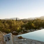 Infinity-Pool von Dalt de Can Suau mit Rattanstühlen und Bergen bei Sonnenuntergang