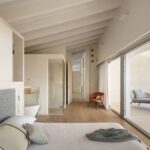 Dormitorio con gran corredera acristalada hacia la terraza, sillón naranja, tumbona y vistas a la montaña