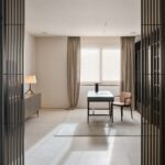 Despacho con escritorio verde, silla rosa, aparador y cortinas de lino tras lamas de madera oscura
