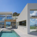 Villa Bonaire 42 con piscina, volúmenes blancos, piedra dorada y grandes cristaleras con vistas al mar