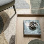 Detail of a natural fibre rug in green and sand beside a timber coffee table