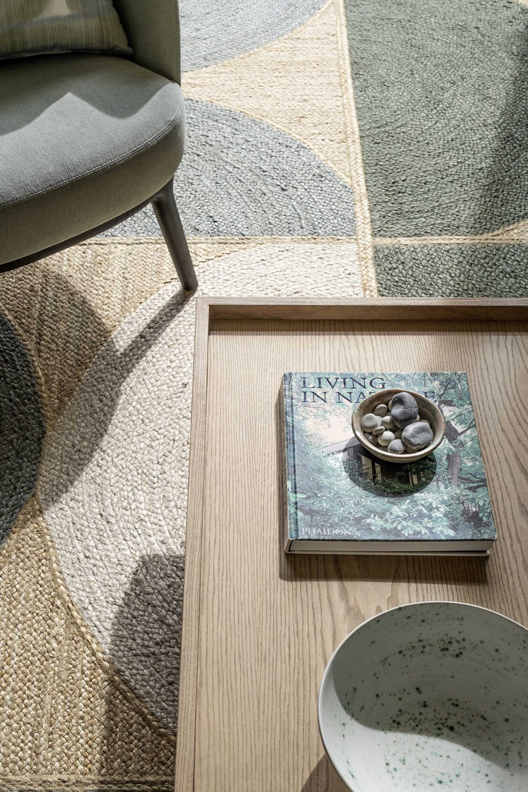 Detail of a natural fibre rug in green and sand beside a timber coffee table