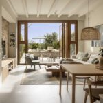 Bright living and dining room with wicker lamps, wooden table and doors open onto the terrace