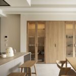 Open kitchen with island, wooden stools and wooden cabinet with fluted glass doors