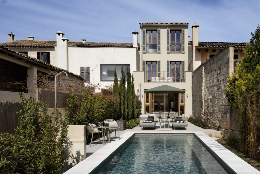 Fachada trasera de SM41 con jardín, cipreses, muro de piedra y piscina alargada