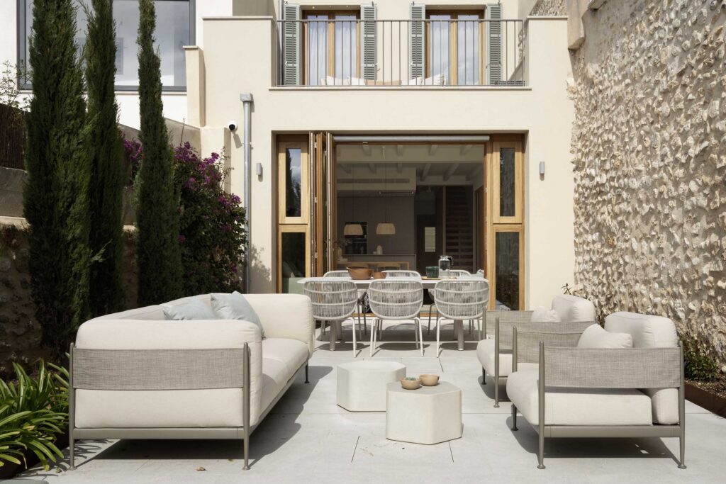Terrace with dining area and sofas in front of the living room, which opens up through folding timber joinery