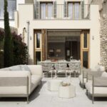 Terrace with dining area and sofas in front of the living room, which opens up through folding timber joinery