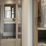 Sliding fluted glass door to the bathroom and open wardrobe with hanging clothes